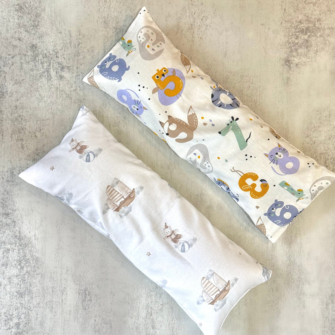 Two long husk pillows with animal design prints on fabric