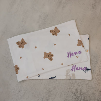 Two baby pillow cases with teddy bear patterns on a textured surface