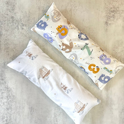 Two long, rectangular beansprout husk pillows with animal patterns on a textured surface
