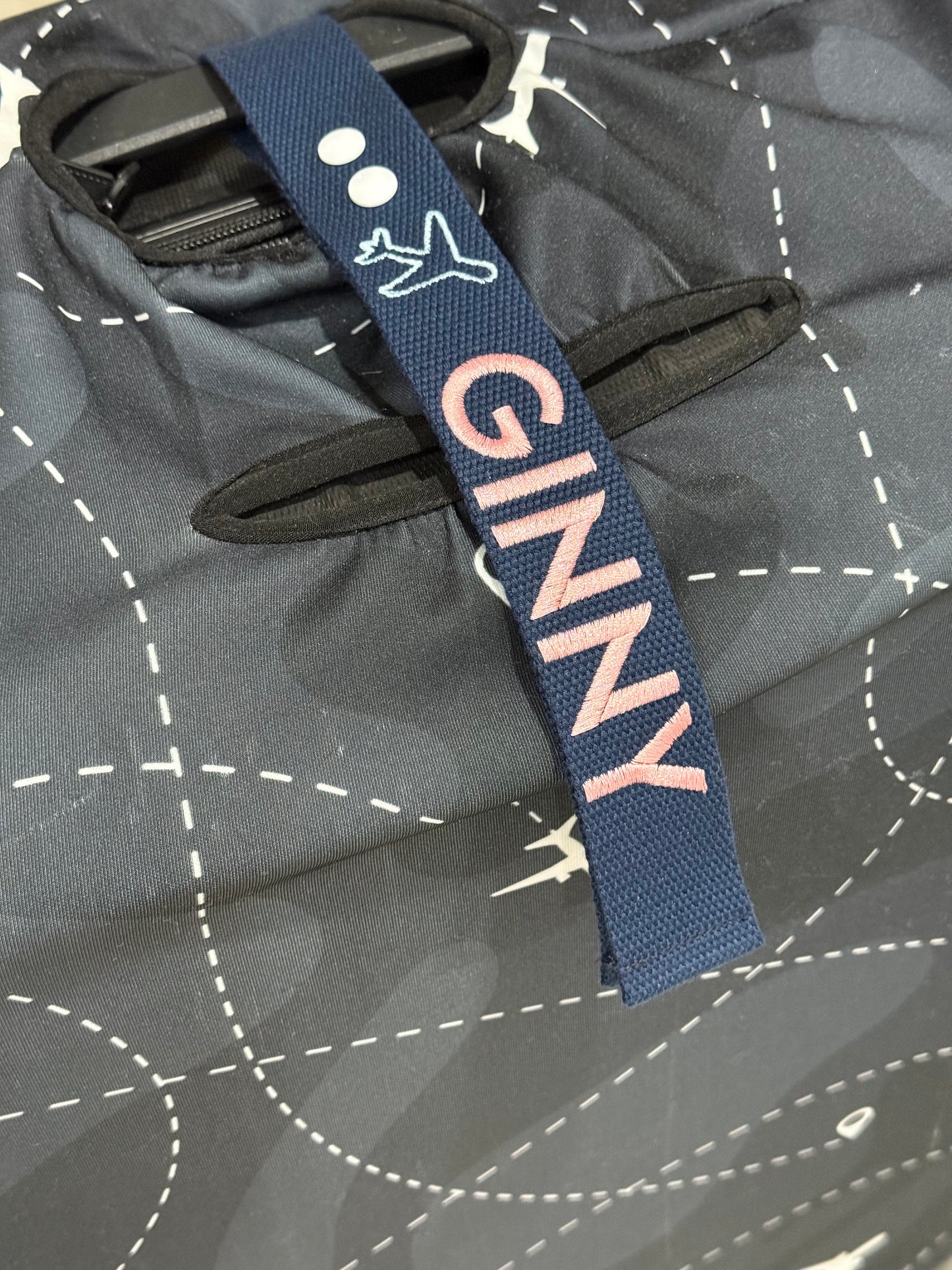 Navy luggage strap with 'GINNY' text on a luggage