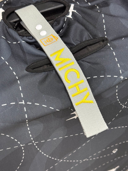 Luggage strap with a 'MICHY' on a dark luggage