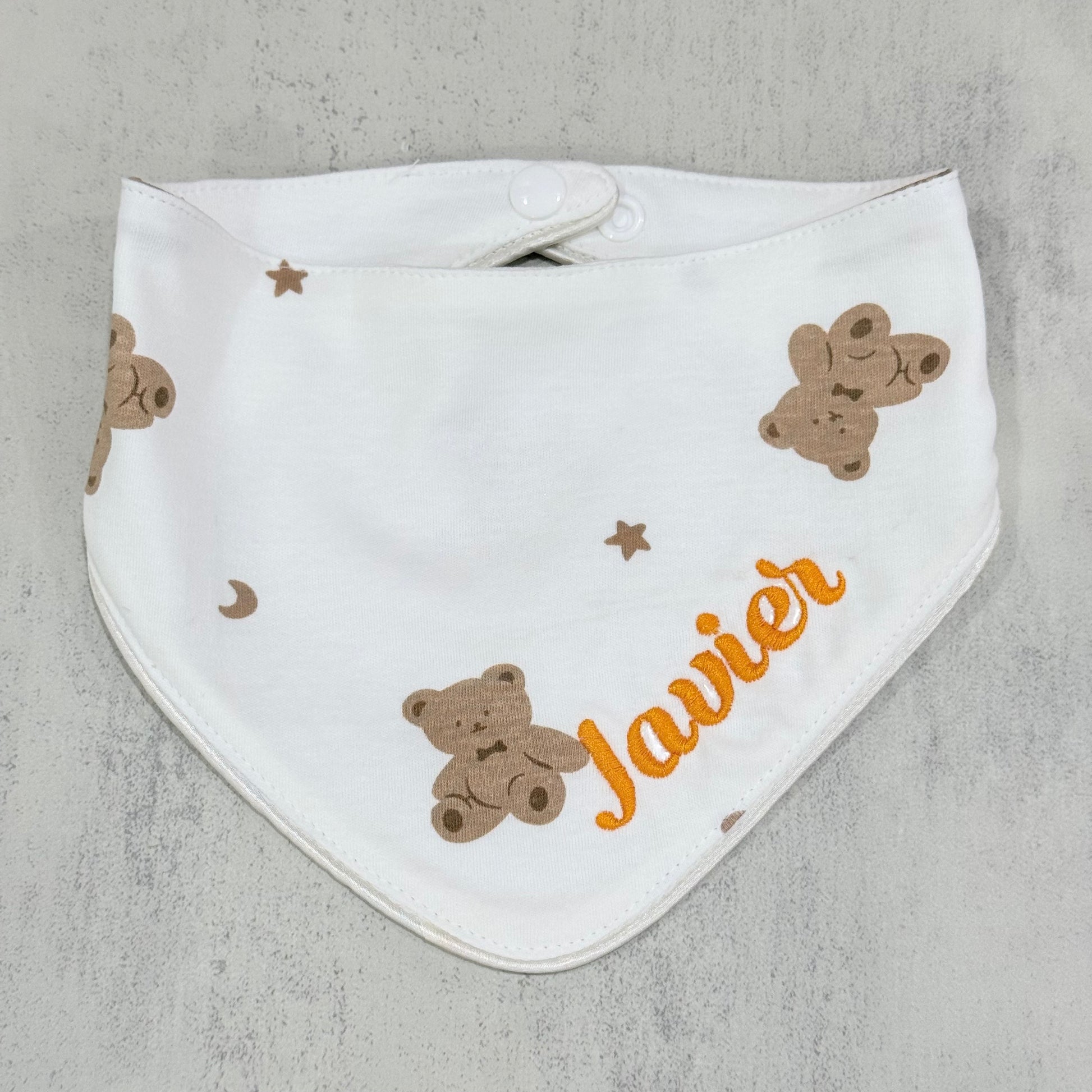 White baby bib with teddy bear patterns and the name 'Javier' on a gray background